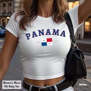 May include: White micro rib baby tee with the word "PANAMA" in navy blue arched lettering. Below the word "PANAMA" is a small Panamanian flag and the text "EST. 1903". The shirt is a crop top.