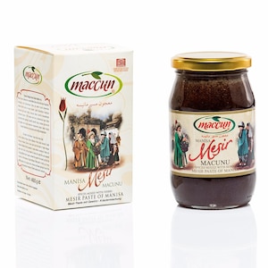 以下が含まれることがあります： マニサ・メシル・マクヌの箱と瓶。スパイスペーストです。箱は白で、緑色のロゴと伝統的な衣装を着た人々の絵が描かれています。瓶は金色の蓋と、同じロゴとテキストのラベルが付いています。