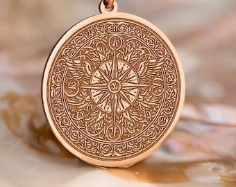 May include: Rose gold pendant necklace featuring a circular pendant with an intricate engraved design. The pendant hangs from a delicate chain. The design includes a compass rose and ornate patterns. The necklace is displayed on a pearlescent surface.