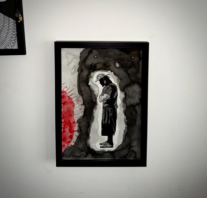 May include: Framed artwork featuring a black and white ink illustration of a person in a hat with arms crossed. The figure is set against a dark, abstract background with red accents. The artwork is encased in a black frame.