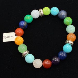 May include: A stretch bracelet featuring multicolored round beads in shades of blue, green, orange, red, purple, and white, interspersed with silver-toned metal spacers. A white rectangular tag with the word Brighton is attached to the bracelet.