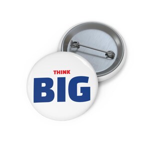 May include: White button with the words "THINK BIG" in red and blue. The button has a metal pin back. The button is round and has a shiny surface.