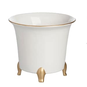 May include: A white ceramic planter with a smooth finish, featuring a wide, flared rim with a thin gold-painted edge. The vessel is supported by three short, rounded feet finished in a metallic gold color, providing a stable base for the container.