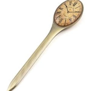 May include: An antique-style letter opener with a clock face design. The oval-shaped clock face features Roman numerals and a vintage aesthetic. The handle is a solid, elongated shape with a metallic finish.