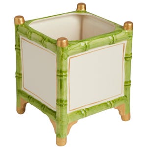 May include: A square ceramic planter featuring a white center panel framed by green bamboo-style molding. The four corners are accented with gold-painted finials at the top and matching gold-painted feet at the base, creating a structured look.