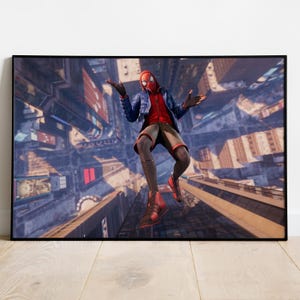 May include: A framed print featuring a character in a red and black suit with a mask, mid-air above a cityscape. The character wears a blue jacket and shorts. The background shows a detailed aerial view of buildings and streets.