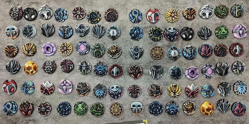May include: A collection of intricately designed, circular decorative objects. Each piece features unique patterns and color combinations, including shades of blue, red, gold, and black. The objects are arranged on a textured, gray surface.