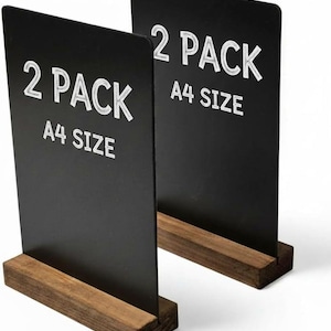 May include: Two black A4 size chalkboard signs with white text that reads "2 PACK". The signs are set in a dark brown wooden base. The signs are ideal for displaying menus or messages.