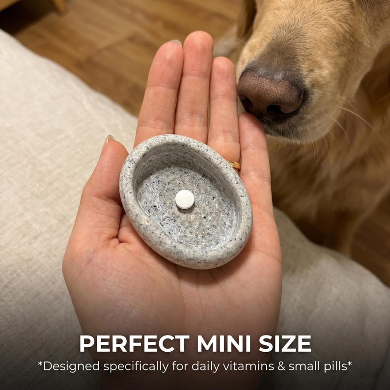 Puede incluir: Un peque&ntilde;o pastillero ovalado de piedra gris con una sola pastilla blanca en su interior. El texto "PERFECT MINI SIZE" y "Designed specifically for daily vitamins & small pills*" est&aacute;n en la parte inferior de la imagen.
