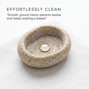 Puede incluir: Un peque&ntilde;o cuenco de piedra de forma ovalada, con un interior liso y pulido. El cuenco es de color beige claro con motas m&aacute;s oscuras y est&aacute; sobre una superficie de lino blanco. El texto "EFFORTLESSLY CLEAN" est&aacute; encima del cuenco.