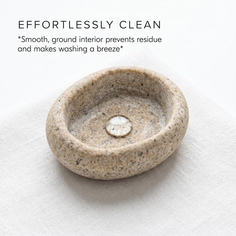 Puede incluir: Un peque&ntilde;o cuenco de piedra de forma ovalada, con un interior liso y pulido. El cuenco es de color beige claro con motas m&aacute;s oscuras y est&aacute; sobre una superficie de lino blanco. El texto "EFFORTLESSLY CLEAN" est&aacute; encima del cuenco.