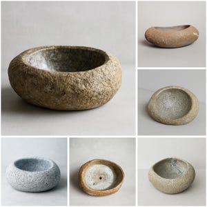 Puede incluir: Una colección de cuencos de piedra de varias formas y tamaños. Los cuencos tienen un aspecto natural y texturizado con tonos de gris, marrón y beige. Los cuencos redondos tienen un interior liso y un exterior rugoso. Estos cuencos decorativos son adecuados para la decoración del hogar.