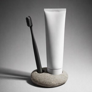 K&ouml;nnte beinhalten: Eine schwarze Zahnb&uuml;rste und eine wei&szlig;e Tube Zahnpasta werden in einem grauen Steinhalter pr&auml;sentiert. Die Zahnb&uuml;rste hat schwarze Borsten. Die Zahnpastatube ist zylindrisch und hat einen wei&szlig;en Deckel. Der Steinhalter ist oval geformt.
