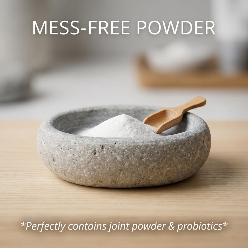 Puede incluir: Un cuenco de piedra gris lleno de polvo blanco y una peque&ntilde;a cuchara de madera. El texto "MESS-FREE POWDER" est&aacute; encima del cuenco. El texto "*Contiene perfectamente polvo para las articulaciones y probi&oacute;ticos*" est&aacute; debajo.