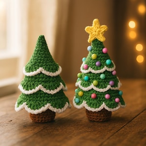 Può includere: Due alberi di Natale all'uncinetto fatti a mano. Uno è verde semplice con bordi smerlati bianchi. L'altro è decorato con perline colorate e una stella gialla in cima. Entrambi gli alberi hanno basi marroni e poggiano su una superficie di legno.