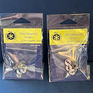 May include: Two clear plastic hanging bags containing silver-colored 10 mm magnetic snaps. Each yellow label features the text 'the Around Bobbin', 'Mini Magnetic Snaps', '10 mm magnetic snaps', and the product code 'ATB-199-HK' printed in black.