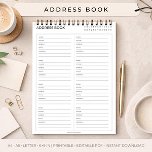 May include: A spiral-bound address book with the title "ADDRESS BOOK" at the top. The pages are white with lined sections for name, phone, mobile, email, and address. A gold pen rests on the right side. The book is 6x9 inches.