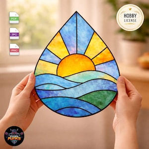 Peut inclure: Un attrape-soleil en vitrail en forme de goutte d'eau représentant un soleil jaune vif se levant sur des vagues bleues et vertes. Le motif est segmenté par des lignes noires, créant un paysage géométrique avec un ciel jaune et des rayons bleus.