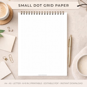 Puede incluir: Un cuaderno de papel de cuadrícula de puntos con espiral y el texto "SMALL DOT GRID PAPER". El cuaderno abierto muestra una cuadrícula de pequeños puntos. Un bolígrafo dorado descansa junto a él. El cuaderno mide 15,24 x 22,86 cm.