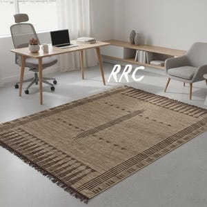 "Handmade Tuareg rug made of woven jute and brown leather strips with geometric tribal patterns and fringe details laid out on the floor."