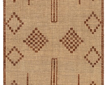 May include: A woven rug with a tan background and brown geometric patterns. The design includes diamond and square shapes, with vertical and horizontal lines. The edges have a fringed border. The letters "RRC" are visible in the corners.