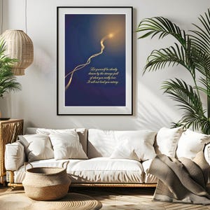 May include: A framed art print with a dark blue background and a glowing, abstract design. The print features gold text that reads, "Let yourself be silently drawn by the strange pull of what you really love. It will not lead you astray."