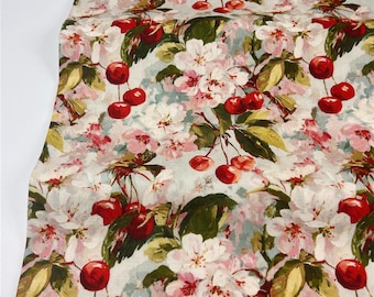 May include: A fabric with a floral pattern featuring red cherries, white and pink blossoms, and green leaves. The design is set against a light blue background, creating a vintage, botanical aesthetic. The fabric is likely used for crafting or home decor.
