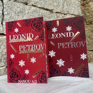 Puede incluir: Dos libros de tapa dura con cubiertas rojas. Las cubiertas presentan el título "LEONID PETROV" en letras plateadas, con rosas decorativas, copos de nieve e ilustraciones de balas. El nombre del autor, "NANOU AD", está en la parte inferior.