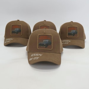 Könnte beinhalten: Eine Sammlung brauner Trucker-Caps mit Mesh-Rückseite. Jede Kappe hat ein quadratisches Patch mit einer Vintage-Auto-Illustration und dem Text "KEIN ROST, NUR CHARAKTER". Auf den Kappen steht auch der Text "VOLVOS AM SEE".