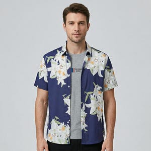 Puede incluir: Una camisa azul marino de manga corta con un estampado floral blanco. La camisa tiene una botonadura frontal y un cuello clásico. El texto "THE COME MUSIC" es visible en la camisa.