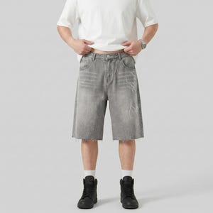 May include: Gray denim shorts with a raw hem and white accents. The shorts have a relaxed fit and feature a faded design. The shorts are paired with black high-top sneakers.