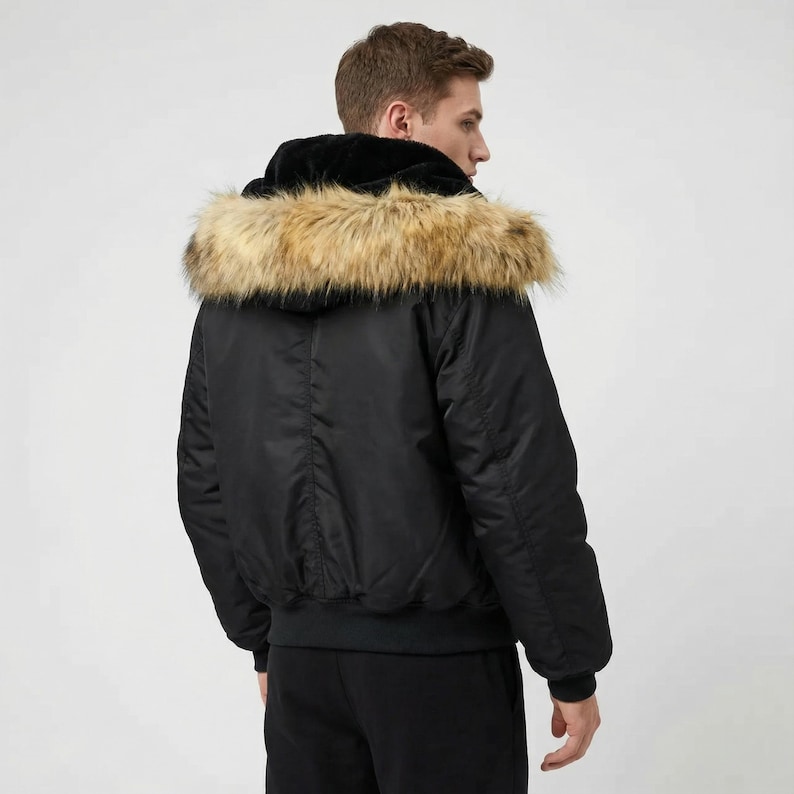 K&ouml;nnte beinhalten: Schwarze Bomberjacke mit Kapuze mit Kunstfellbesatz. Die Jacke hat einen gerippten Saum und B&uuml;ndchen. Das Model tr&auml;gt eine schwarze Hose. Die Kapuze der Jacke ist mit schwarzem Samt gef&uuml;ttert.
