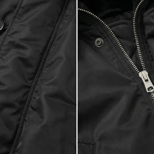 K&ouml;nnte beinhalten: Nahaufnahme einer schwarzen Jacke mit glatter, gl&auml;nzender Textur. Die Jacke hat einen Rei&szlig;verschluss und einen Knopfverschluss. Die Kn&ouml;pfe sind dunkel und rund. Der Rei&szlig;verschluss ist silberfarben. Die Jacke scheint aus einem synthetischen Material zu sein.