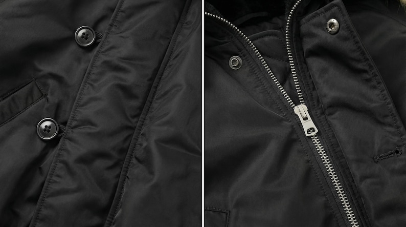 K&ouml;nnte beinhalten: Nahaufnahme einer schwarzen Jacke mit glatter, gl&auml;nzender Textur. Die Jacke hat einen Rei&szlig;verschluss und einen Knopfverschluss. Die Kn&ouml;pfe sind dunkel und rund. Der Rei&szlig;verschluss ist silberfarben. Die Jacke scheint aus einem synthetischen Material zu sein.