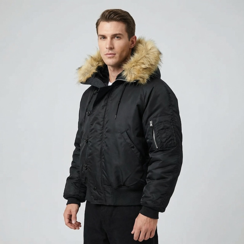 K&ouml;nnte beinhalten: Schwarze Bomberjacke mit Kapuze mit Kunstfellbesatz. Die Jacke hat eine Rei&szlig;verschlusstasche am linken &Auml;rmel, eine Knopfleiste und einen gerippten Saum. Die Jacke besteht aus einem strapazierf&auml;higen, wasserabweisenden Material.