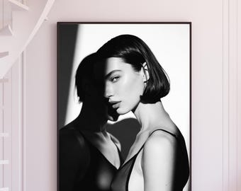 Retrato artístico em preto e branco, sombra cinematográfica de mulher com dupla iluminação, pôster minimalista para impressão em formato digital.