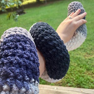 Puede incluir: Un conjunto de tres calentadores de brazo de ganchillo en tonos de azul, gris y blanco. Los calentadores de brazo est&aacute;n hechos de un hilo suave y texturizado y parecen hechos a mano. Los colores se mezclan en un efecto degradado.