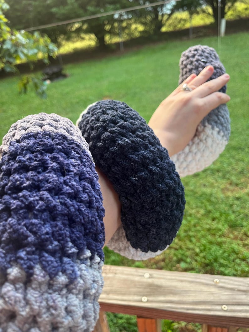 Puede incluir: Un conjunto de tres calentadores de brazo de ganchillo en tonos de azul, gris y blanco. Los calentadores de brazo est&aacute;n hechos de un hilo suave y texturizado y parecen hechos a mano. Los colores se mezclan en un efecto degradado.