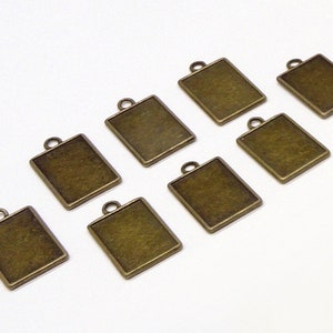 May include: Eight antique gold-toned metal square pendant charms with a loop at the top for attaching to jewelry or other crafts.