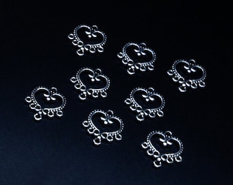 May include: Ten silver-toned heart-shaped metal charms with intricate designs and multiple loops. Each charm has a delicate floral pattern and five loops.