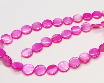 May include: A strand of pink round shell beads. The beads are smooth and have a slight iridescent sheen.