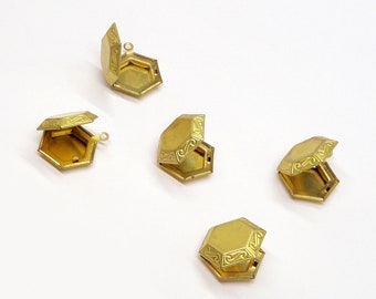 May include: Five gold-colored hexagonal trinket boxes with intricate designs. The boxes are open and have a hinged lid.