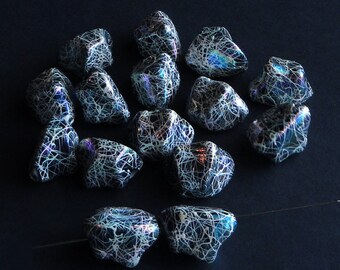 May include: A group of 13 iridescent black and white glass beads with a web-like pattern. The beads are irregularly shaped and have a glossy finish.