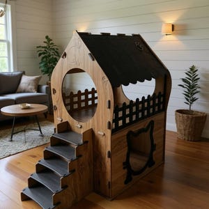 May include: Wooden pet house with a house-shaped design. Features a black roof, a circular opening, and a small fence. Includes a cat-shaped opening and steps for easy access. The house is made of light brown wood.
