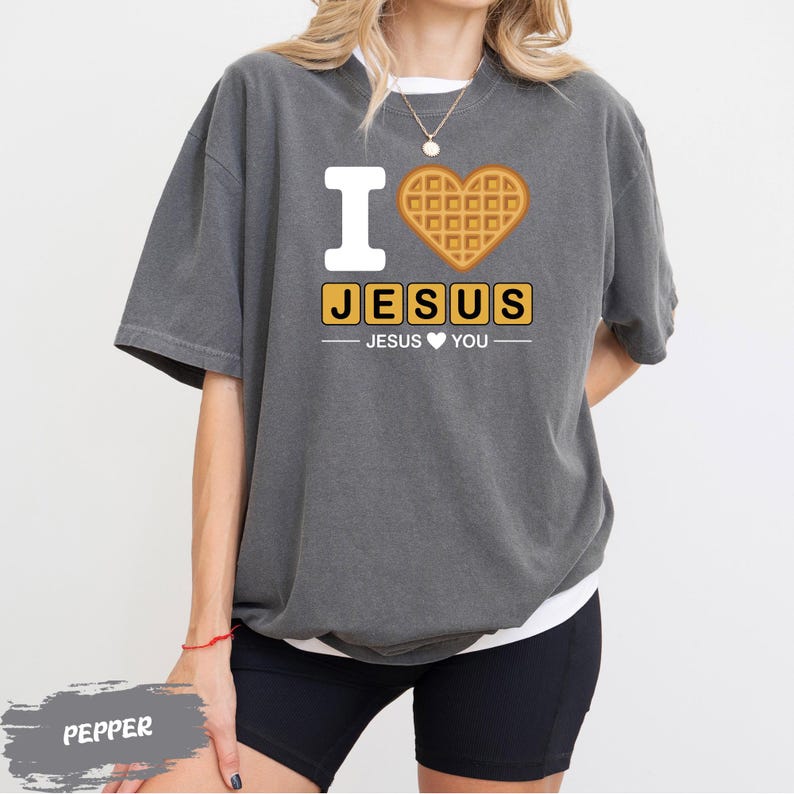 A person wearing a gray t-shirt with a graphic design that says "I ♥ JESUS" and a heart-shaped waffle.