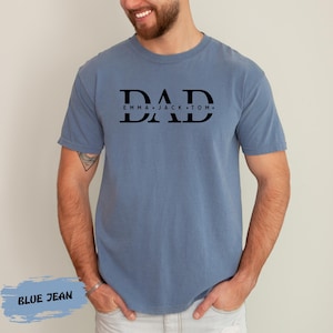 A man wearing a blue t-shirt with the text "DAD" printed on it.