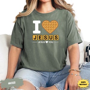 A woman wearing a green t-shirt with a heart-shaped waffle and the text "I ♥ JESUS YOU" printed on it.