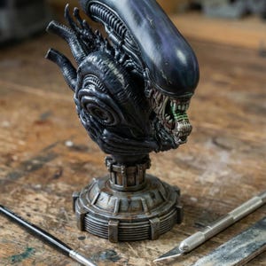 Puede incluir: Busto detallado de Alien en tonos oscuros, con un diseño biomecánico. La escultura presenta una cabeza amenazante con dientes afilados y un cráneo alargado distintivo. Se apoya sobre una base metálica detallada, con herramientas como un pincel y un cuchillo.
