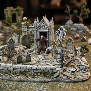 Può includere: Un diorama cimiteriale in miniatura con un mausoleo in pietra, diverse lapidi contrassegnate con RIP, una figura di vampiro, un fantasma, una creatura accovacciata e due figure umane. La scena include un basso muro di pietra e detriti.