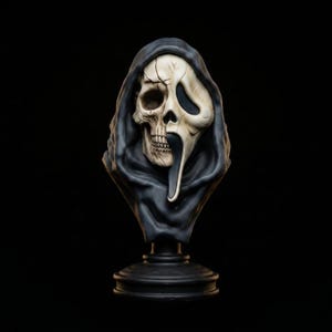 Puede incluir: Un busto decorativo con un diseño dividido que combina un cráneo humano realista en un lado con la icónica máscara de fantasma blanca alargada en el otro. La figura está envuelta en una capa oscura con capucha y se asienta sobre una base.